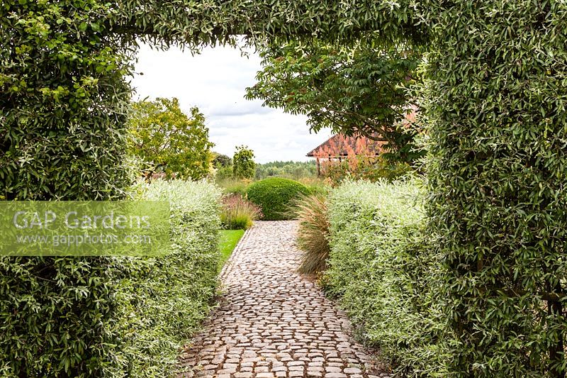View down cobbled stone path in The Walled Garden at Bury Court Gardens, Hampshire, UK.