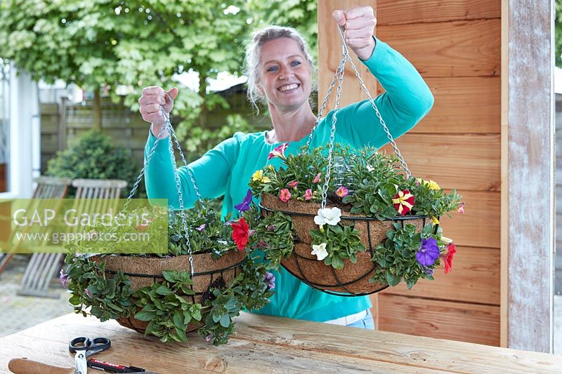 Lady holding two completed hanging baskets