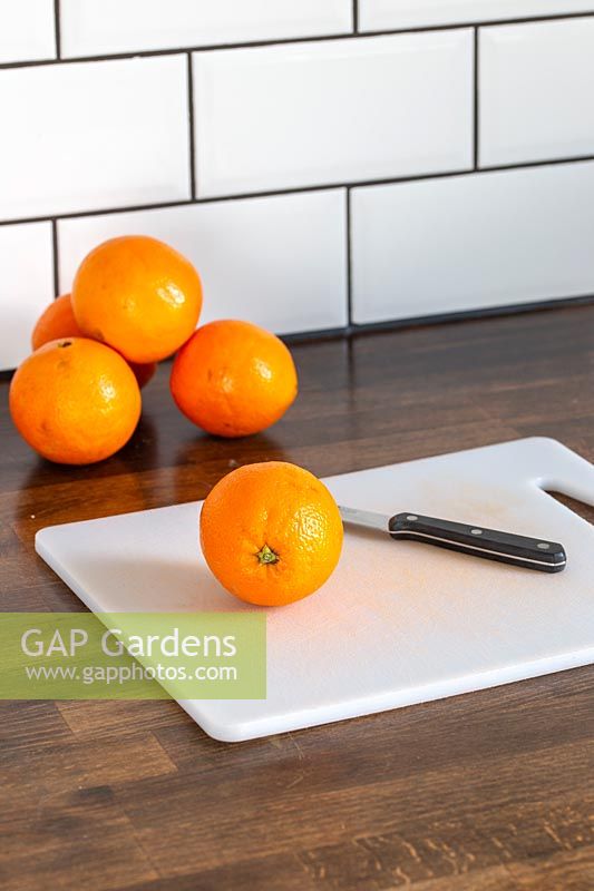 Oranges, chopping board and knife on kitchen worktop