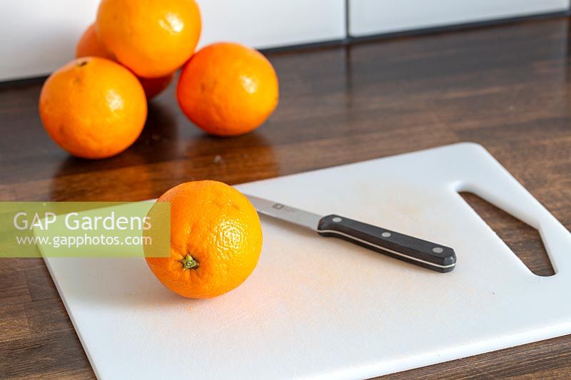 Oranges, chopping board and knife on kitchen worktop