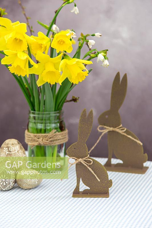 Arrangement with spring flowers and easter decorations on Gingham tablecloth. 