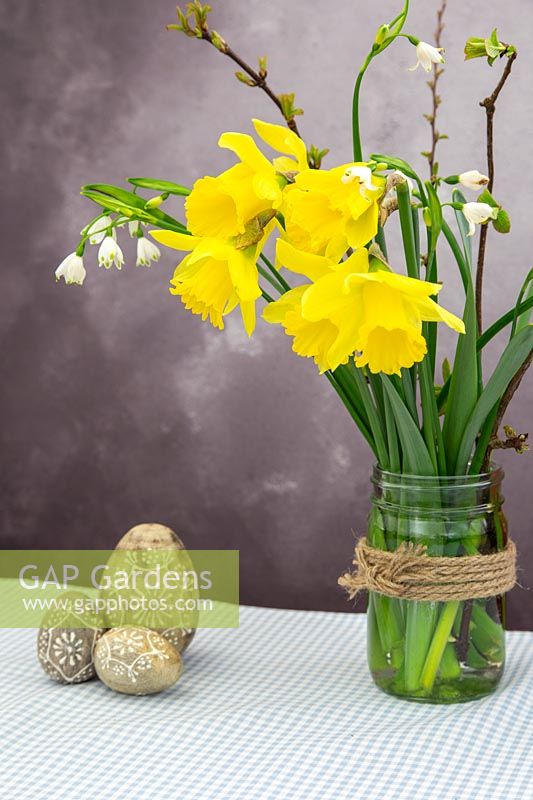 Arrangement with spring flowers and easter decorations on Gingham tablecloth.