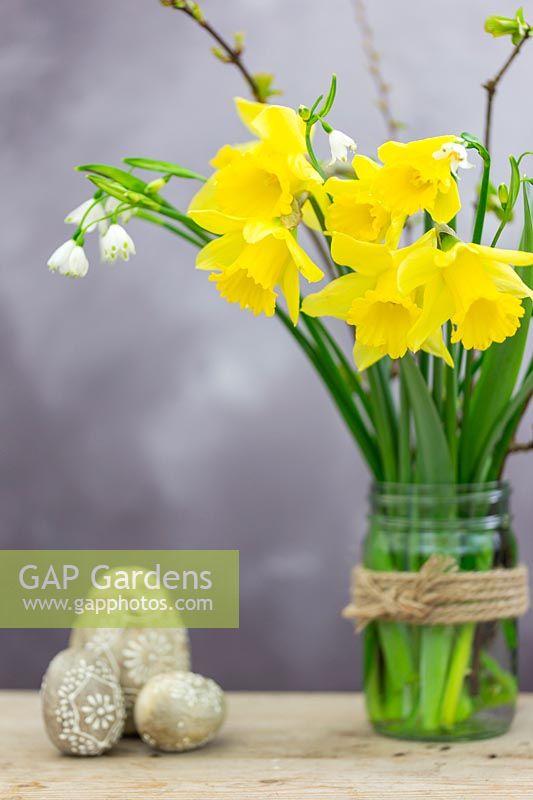 Easter arrangement with Daffodils, spring snowflake and decorated wooden Easter eggs.
