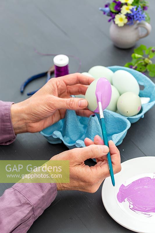 Woman painting the empty egg shell with paint brush