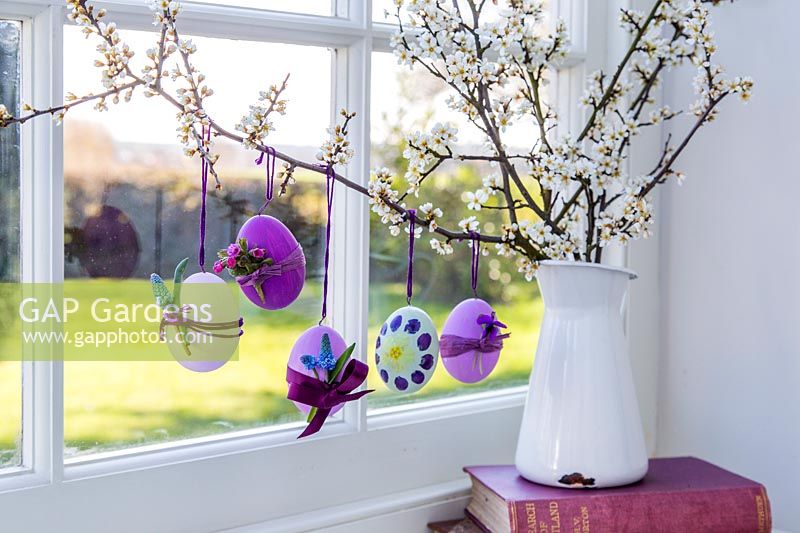 Decorated Easter eggs hanging on branches in windowsill