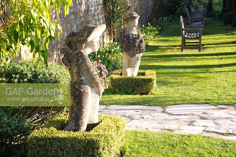A pair of sculptures by Simon Verity, frame a gate out of the main garden. Barnsley House, Cirencester, Glos, UK. 