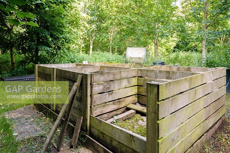 Composting area with multiple wooden bays and tumblers.