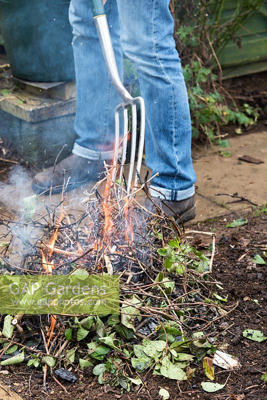 Tending a small bonfire with a garden fork