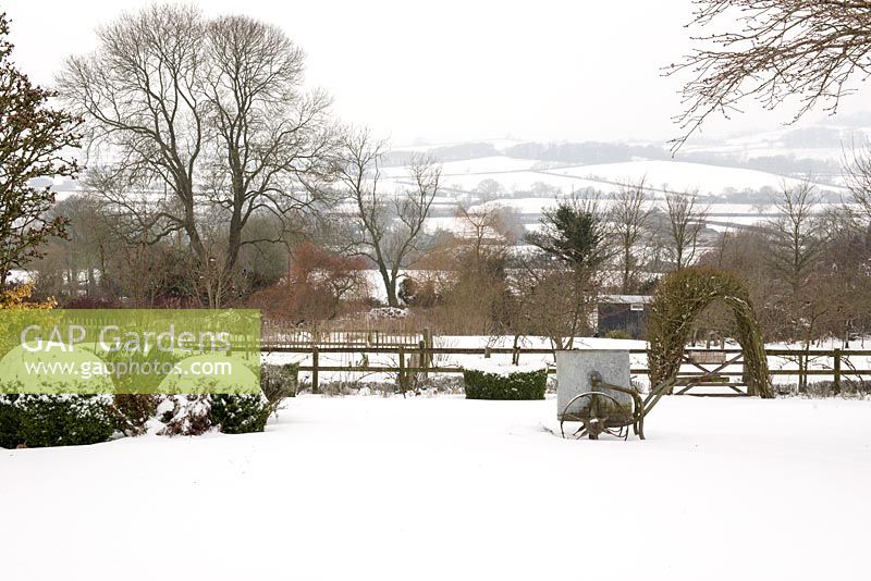Snow-covered lawn with old water bowser with views across the white hills of the Blackmore Vale