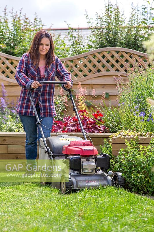 Woman cutting lawn with petrol lawn mower