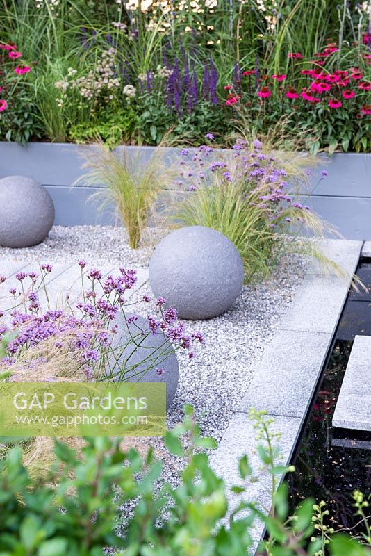 Stone ball features on gravel with Stipa tenuissima and Verbena bonariensis - Secured by Design, RHS Hampton Court Palace Flower Show, 2018.