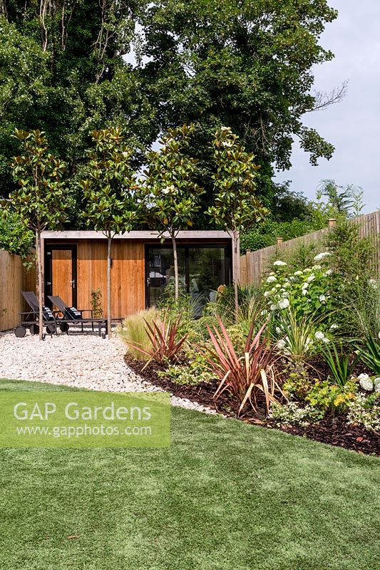 General view of garden with artificial lawn, mixed borders, garden room and white gravel patio area Contemporary garden in Dulwich 