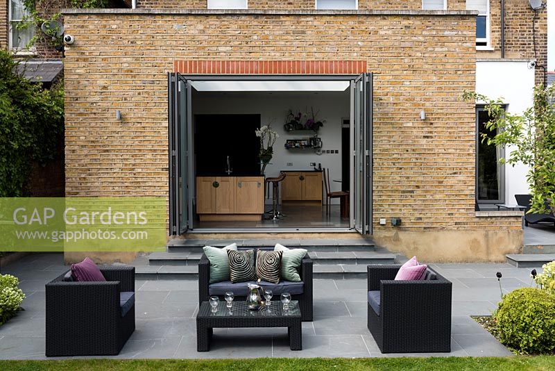 Lounge furniture on patio with view to house extension with bifold doors. 
