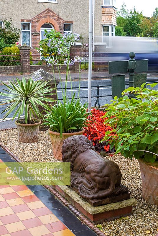 Front garden with tiled path and lion statue. The Secret Garden at Serles House, Wimborne, Dorset, UK