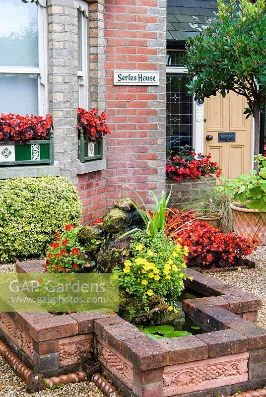 Front garden containing a water feature,planting and window boxes. The Secret Garden at Serles House, Wimborne, Dorset, UK