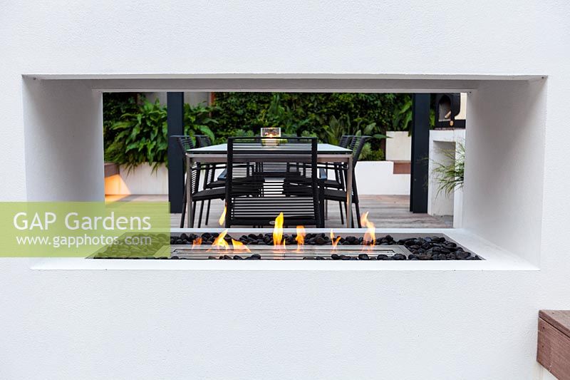 Modern London garden planted with lush foliage, view through fireplace