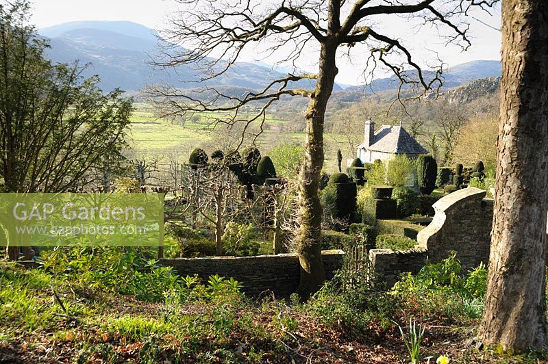 View down over the buildings and gardens of Plas Brondanw from the wooded hillside above. Plas Brondanw, Penrhyndeudraeth, Gwynedd, Wales