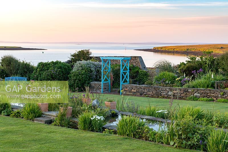 Early morning breaks over the coastal garden at Quoy of Houton, Orkney, unveiling an 18-metre-long rill. 