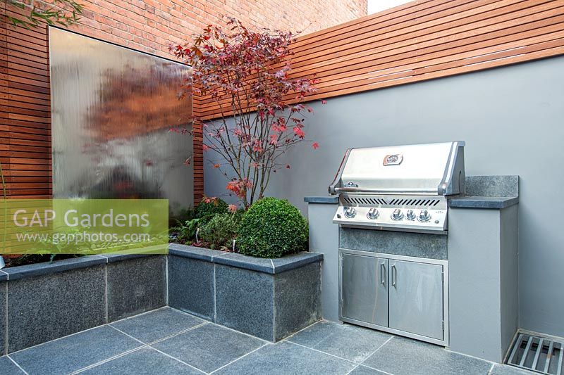BBQ with Acer palmatum in raised integral bed with steel water wall, London