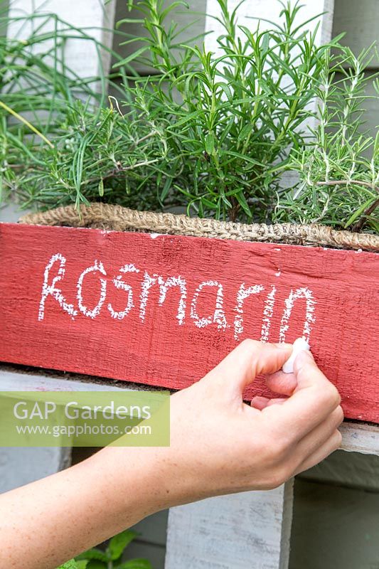 writing name of herb on pallet planter with chalk.