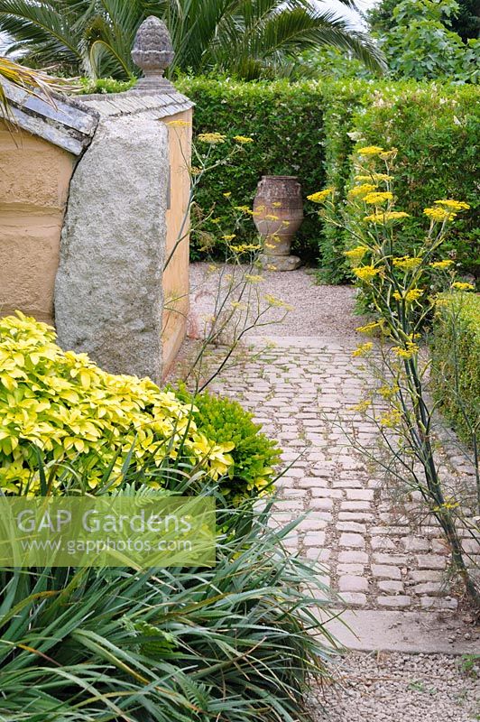 A path of stone sets leads into the garden past self seeded fennel.