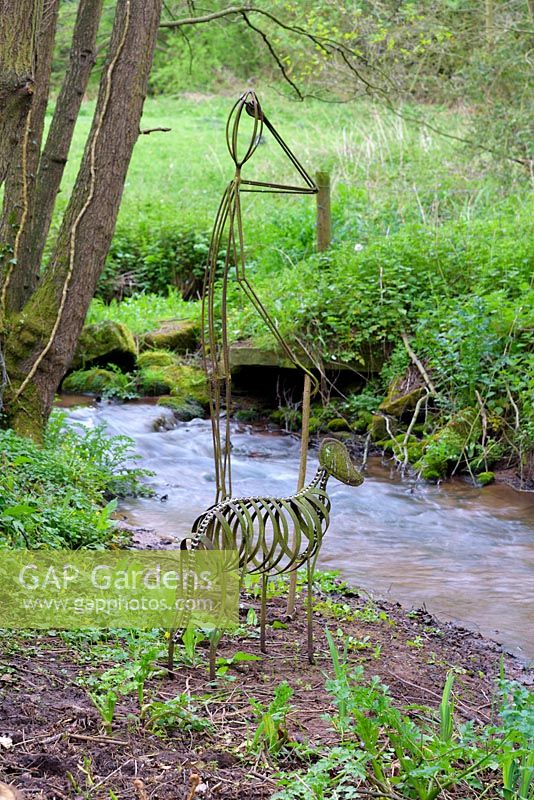 Welded metal sculpture of man and dog beside stream, Ross-on-Wye, Herefordshire