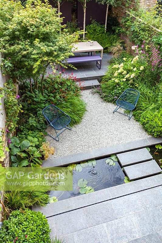 Overview of paved patio area with narrow garden pond. Garden designed by John Davies Landscape.