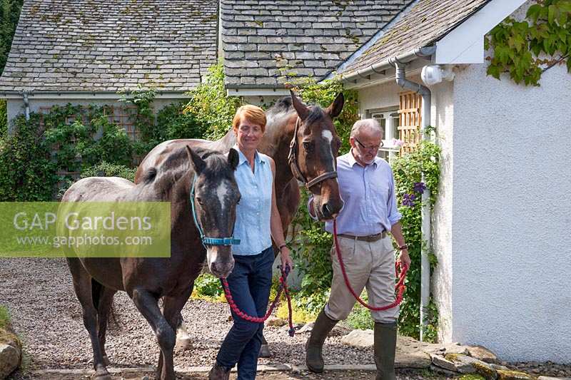 Ian and Clare Alexander leading horse and pony  past  house