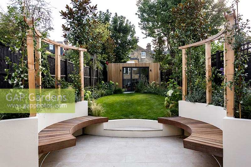 Contemporary garden with circular pergola area, with wooden seating. 