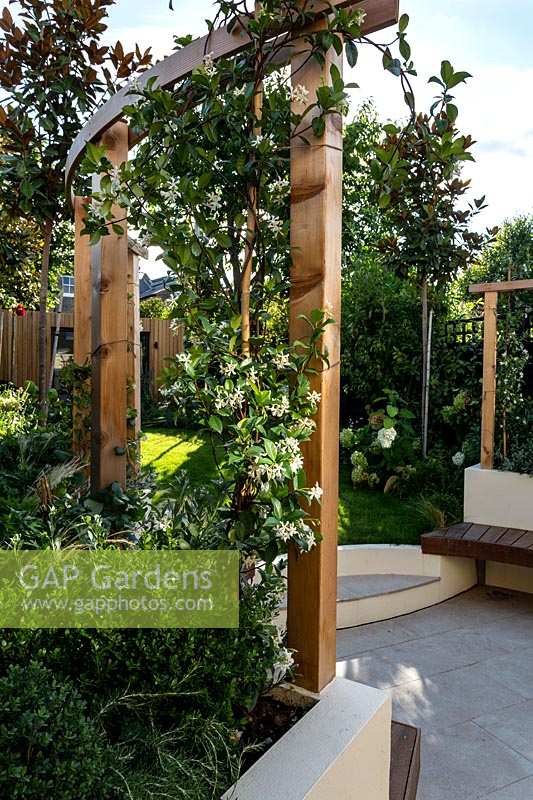 Garden with circular pergola area, with wooden seating.  