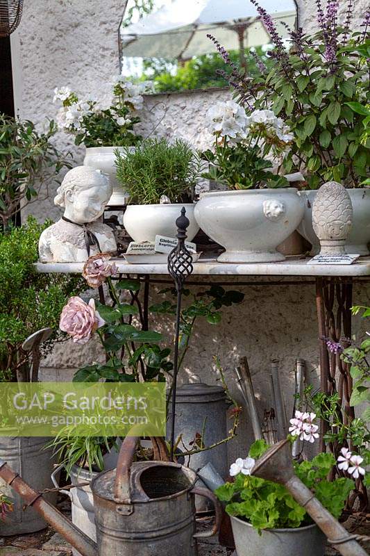 Display of collectables, some planted up, against a wall with vintage tools underneath