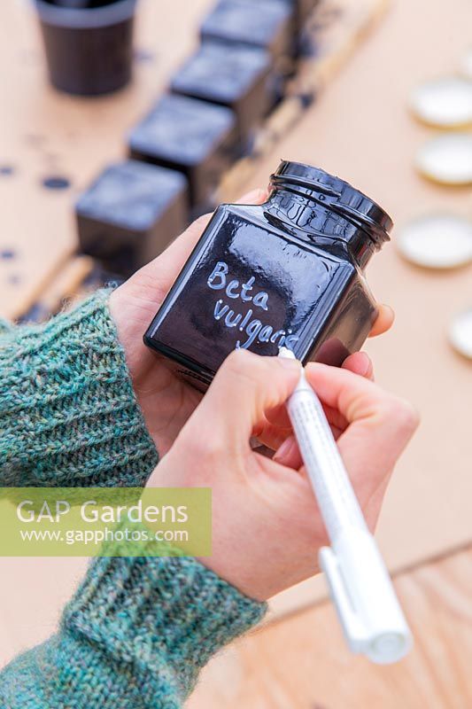 Woman writing with chalk marker pen onto painted glass jar.