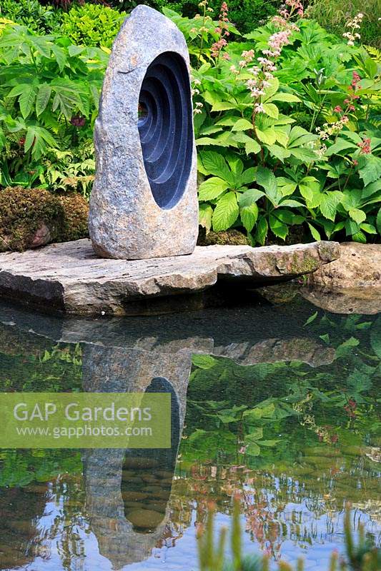 View to the focal stone sculpture on rocks reflected in a pool. 'At One With ... A Meditation Garden', designed by Peter Dowle, RHS Malvern Spring Festival, 2017.

