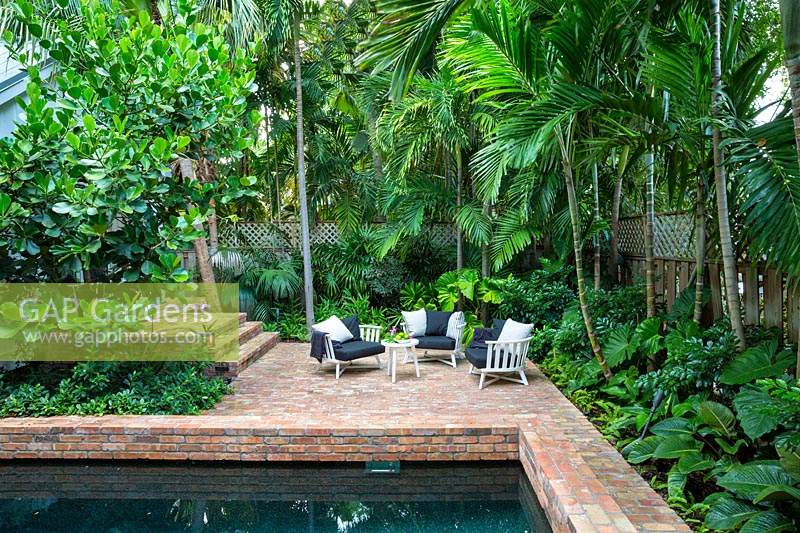 White garden furniture in paved tropical garden. Key West Classic Garden, designed by Craig Reynolds. Key West, Florida, USA.
