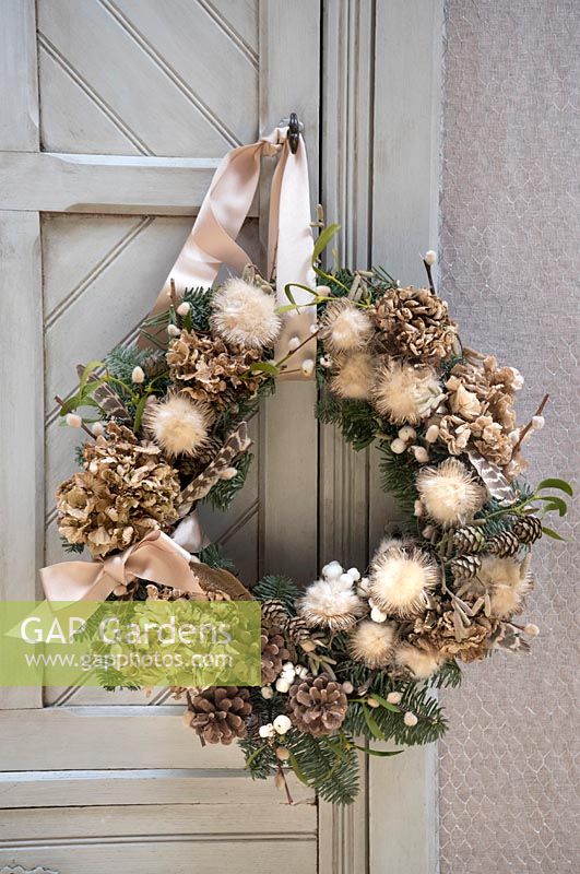 Natural wreath with Hydrangea, fir and feathers, hanging on cupboard door
