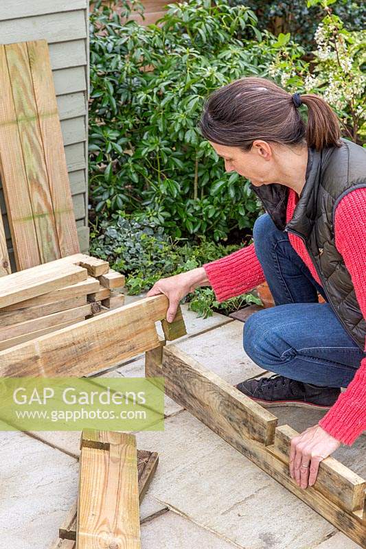 Woman assembling corners of raised planter, fitting together the pieces of each half lap joint