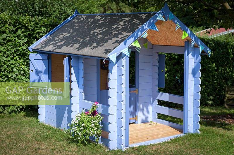 Blue painted children's playhouse in garden. 