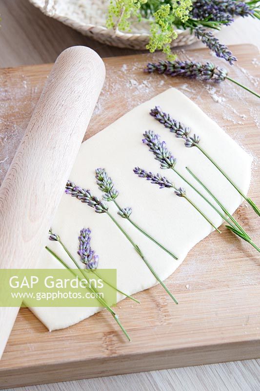Cut lavender flowers being pressed into salt dough with rolling pin 