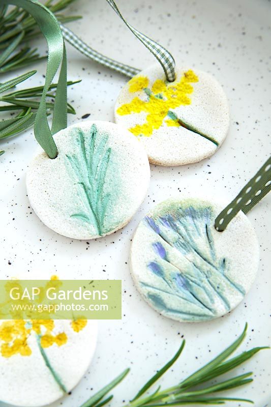 Gift tags on ribbons made with salt dough and decorated with pressed and painted flowers 