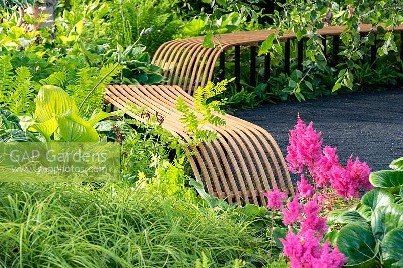 Contemporary curved, slatted wooden benches at the RHS Hampton Court Palace Garden Festival 2019. Sponsor: Smart Energy GB.
