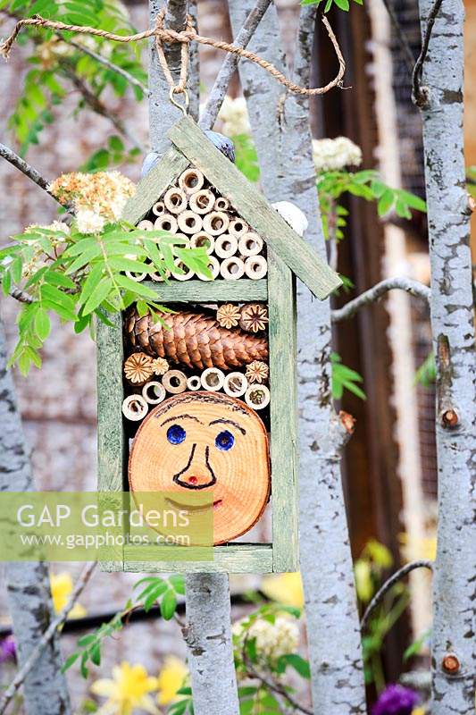 The Montessori Centenary Children's Garden. Insect hotel or bug hotel with smily face carved in a large log end. Sponsor:  Montessori Centre International