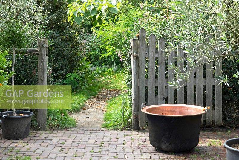 Copper boiler tub in front of the garden fence.
