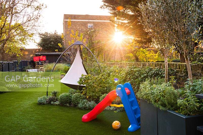 View across the garden with artificial grass, the slide and cacoon hanging tent. 