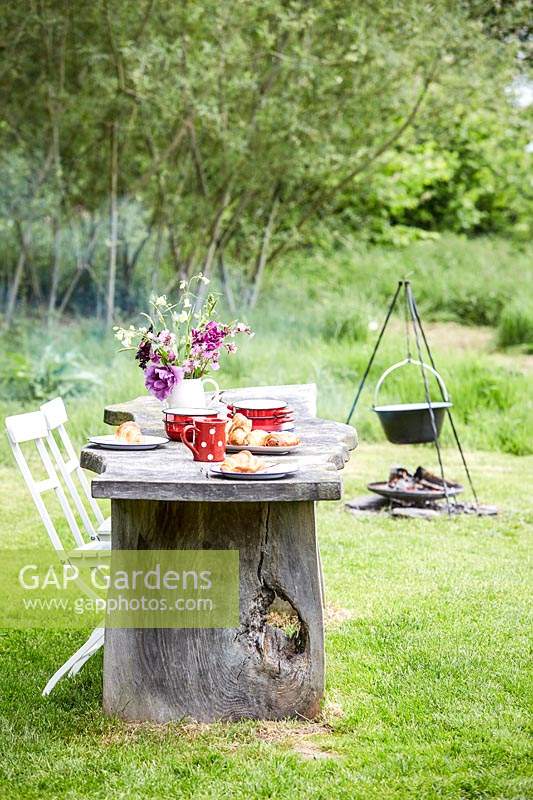 Rustic wooden table and chairs, table set for breakfast - fire place with cooking facilities in background