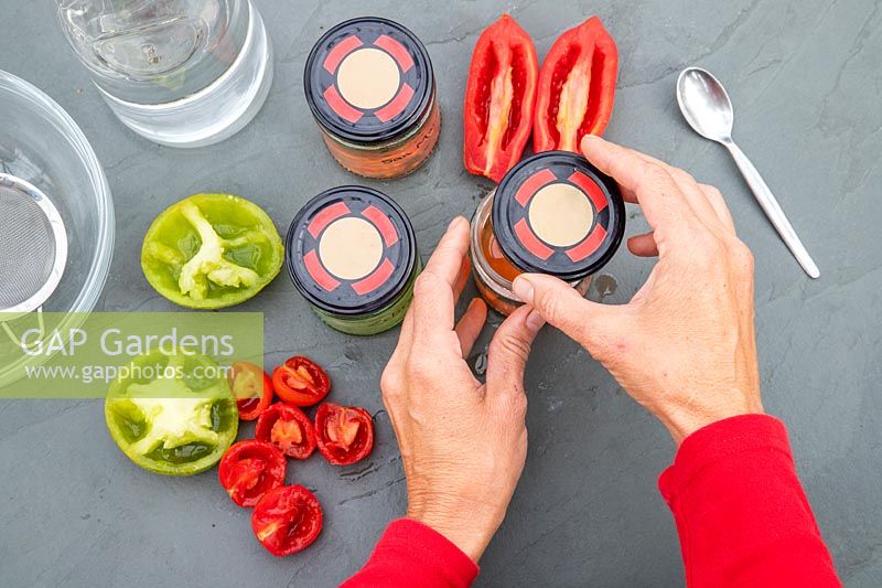 Woman adding lids to the jam jars