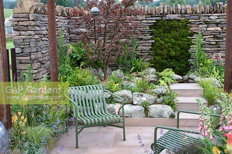 Seating area leading to naturalistic planting in the 'Elements of Sheffield' garden at the RHS Chatsworth Flower Show 2019.