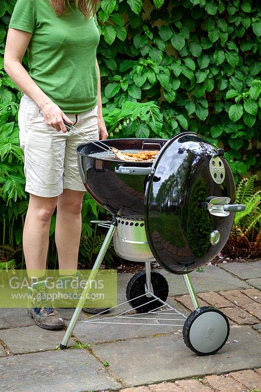 Using a Weber barbecue on a patio in summer