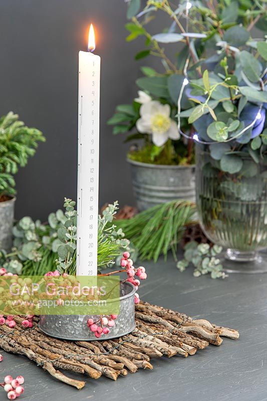 Metal candle holder with calendar candle decorated with pink Rowan berries