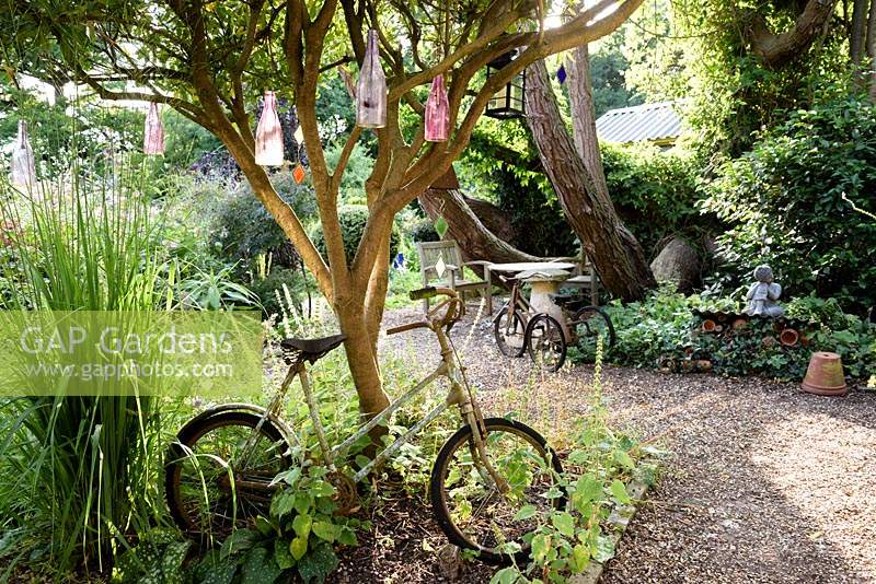 Vintage children's bike and tricycle used as decorative features, under a tree with hanging glass bottles