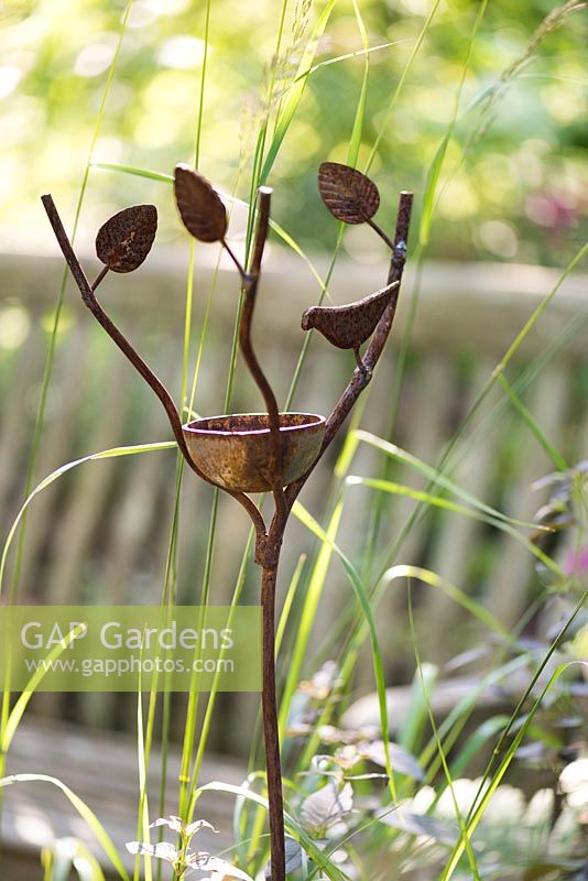 Metal bird feeder with leaves and bird by Jason Thompson